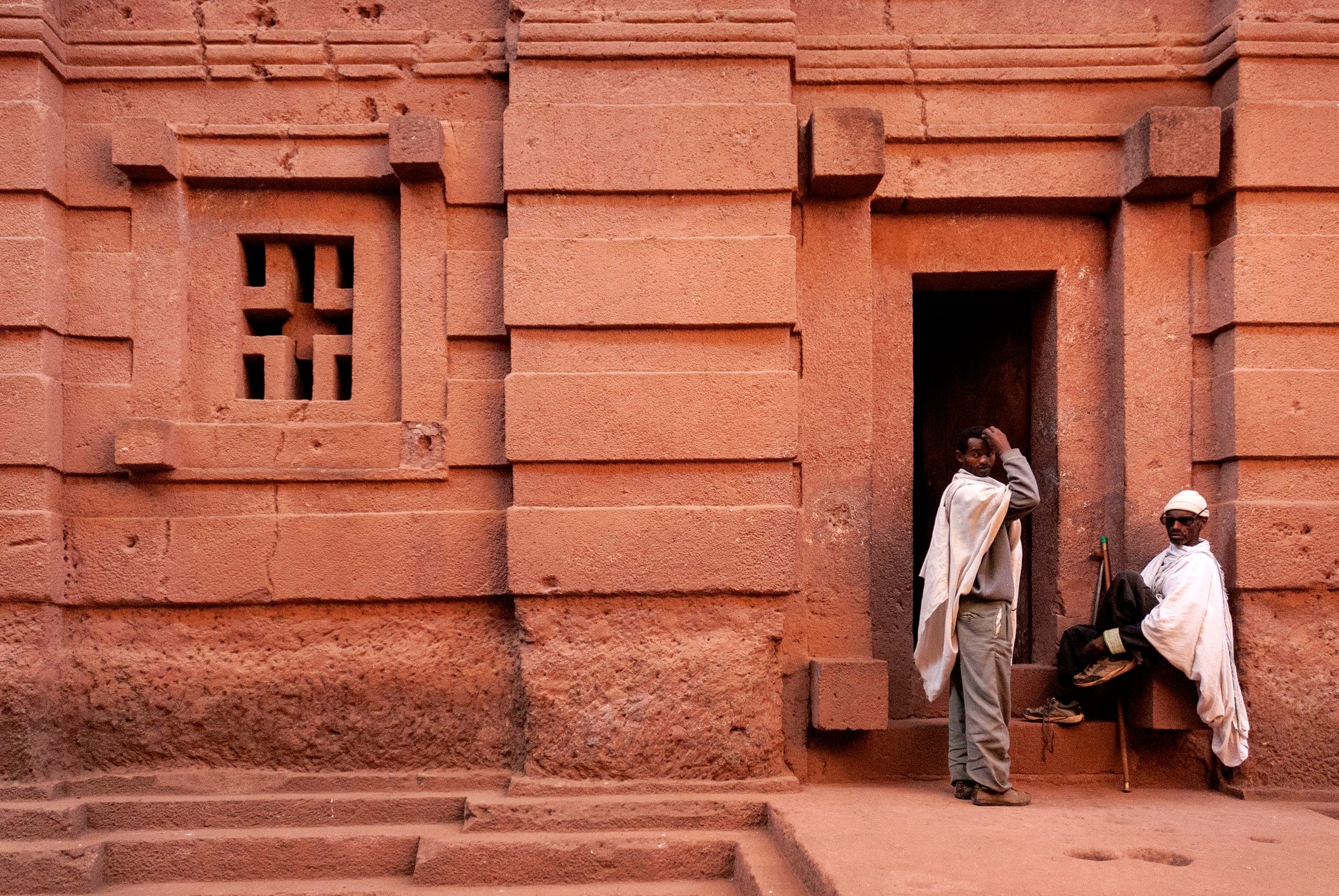 Felsenkirche in Lalibela – rotes Vulkangestein mit eingehauenen Kreuzfenstern und Pilgern, Äthiopien