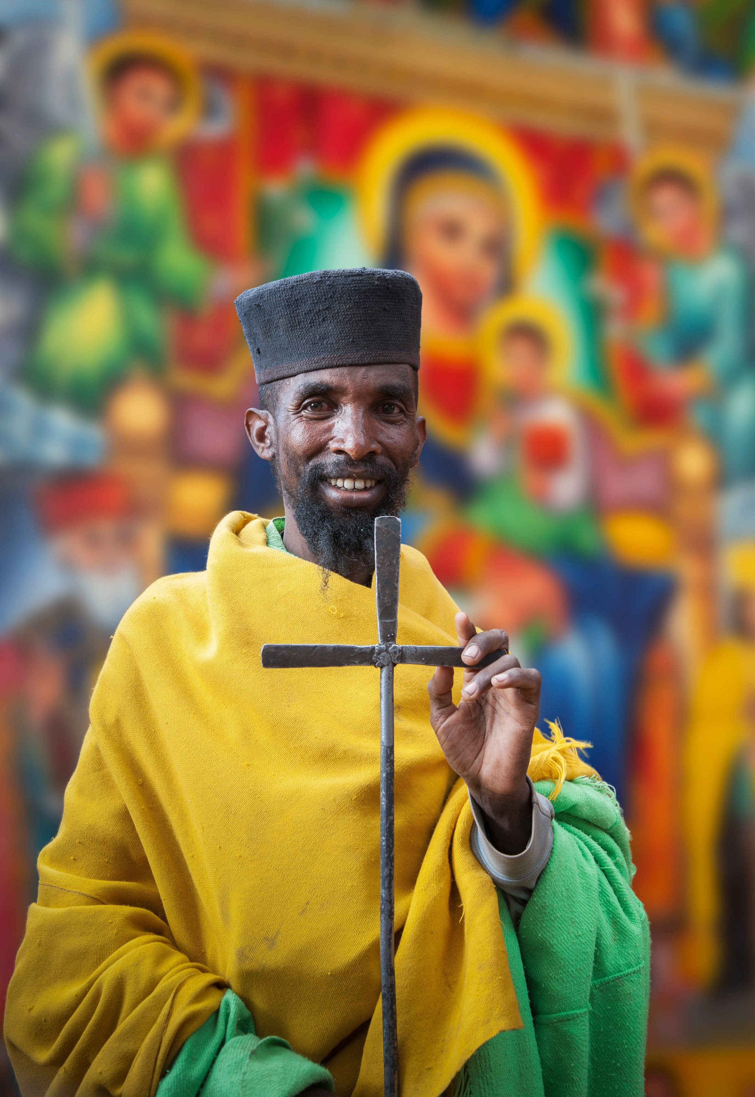 Äthiopisch-orthodoxer Priester in Lalibela – Geistlicher in traditionellen Gewändern mit Metallkreuz vor religiösen Wandmalereien