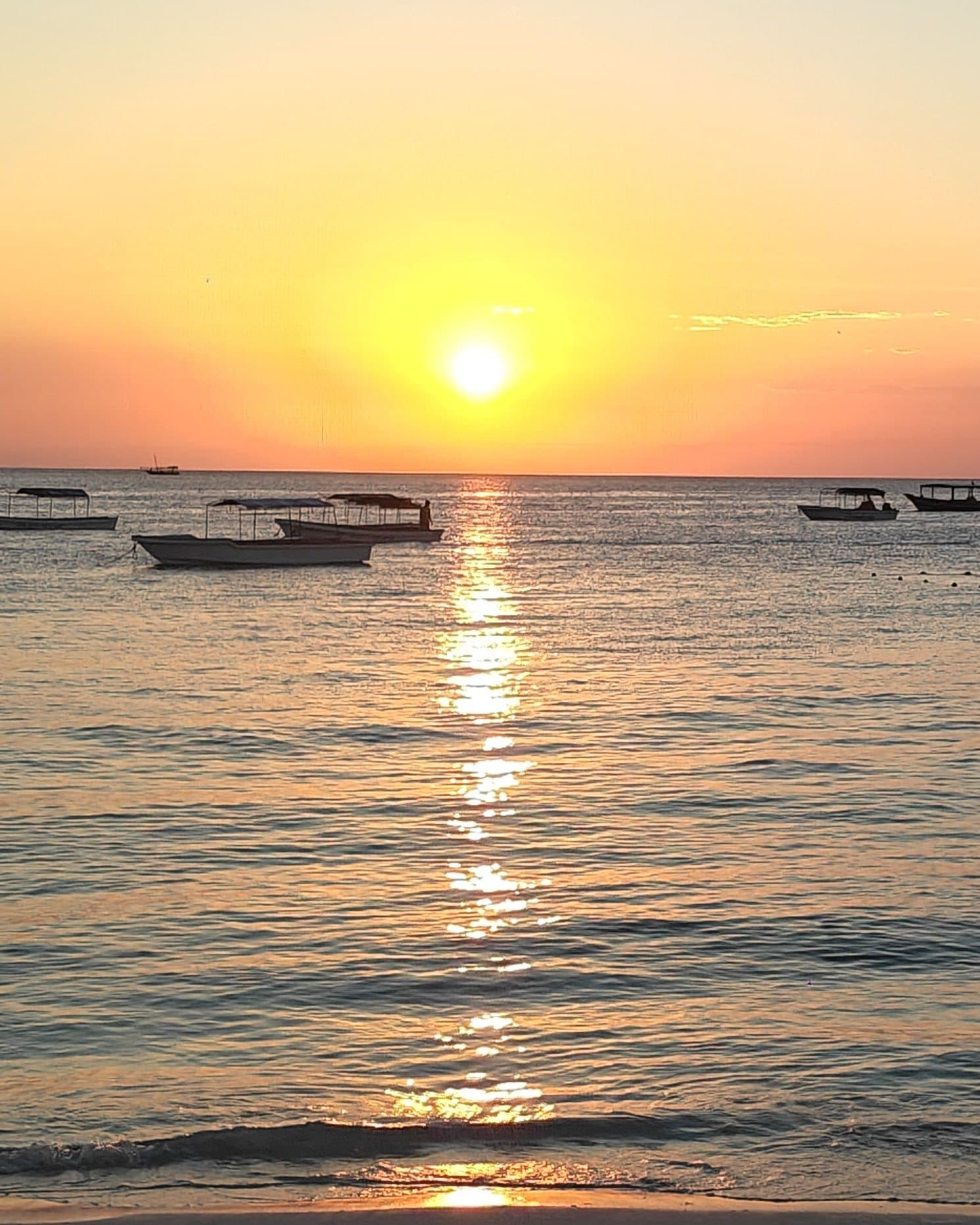 Sonnenuntergang über dem Meer vor Nungwi mit Booten und einer Bojenleine im Wasser