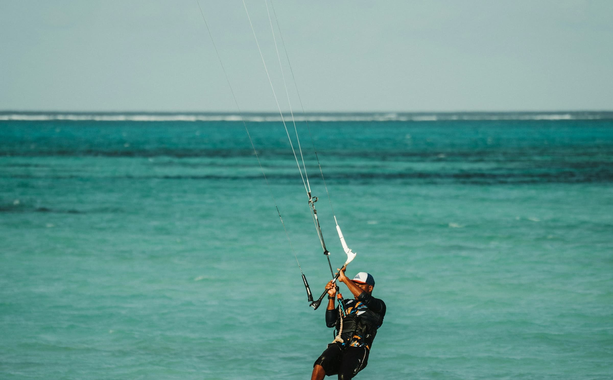 Kitesurfer springt über türkisfarbenes Wasser vor der Küste Sansibars