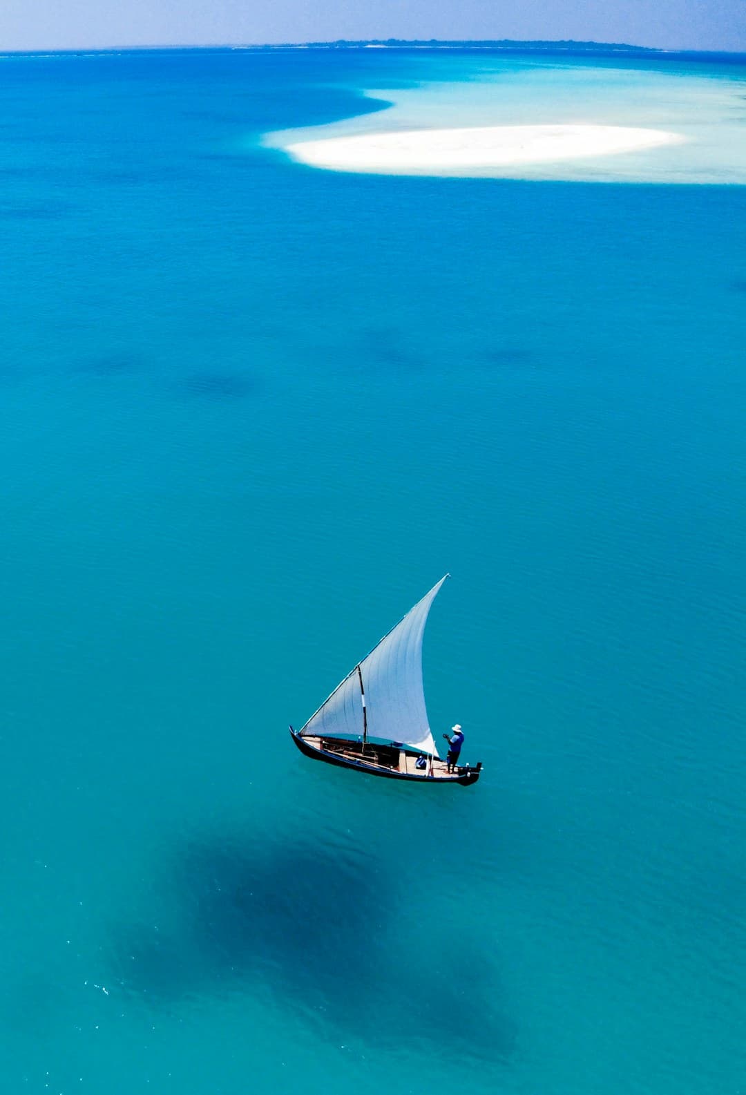Weiße Dhow segelt auf türkisfarbenem Ozean