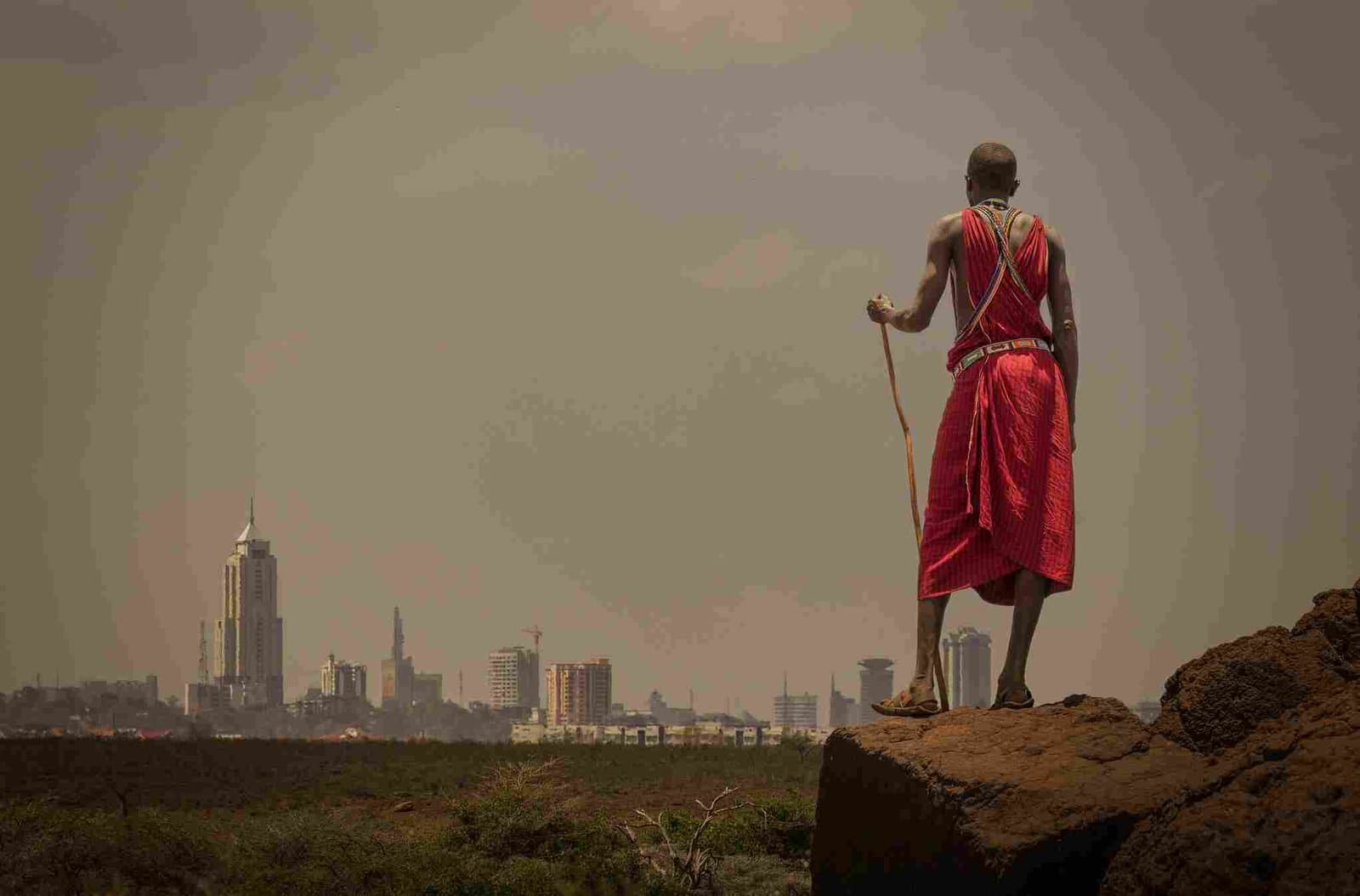Massai-Krieger blickt von einem Hügel auf die moderne Skyline Nairobis