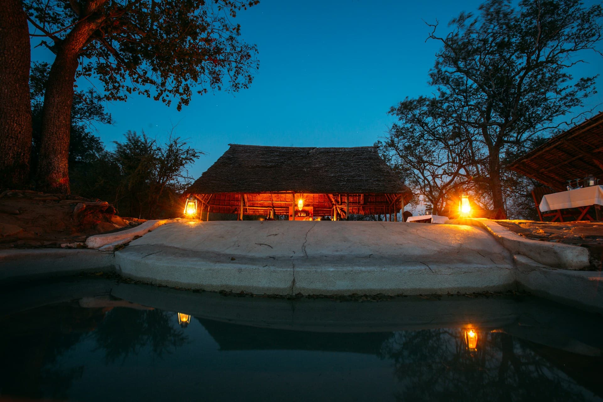 Beleuchtete Safari-Lodge mit Pool in der Abenddämmerung
