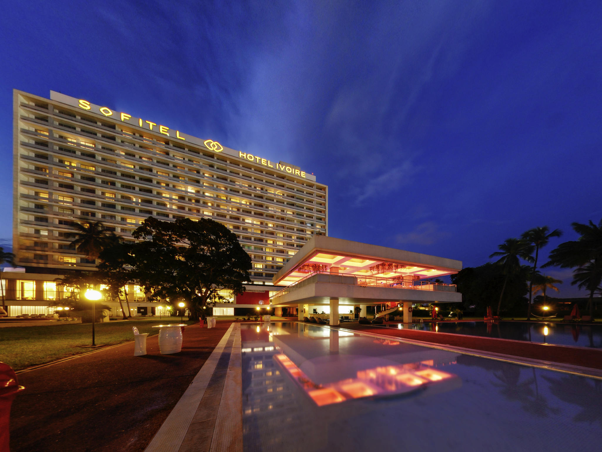 Das Sofitel Abidjan Hotel Ivoire am Abend, beleuchtet, mit Poolanlage im Vordergrund