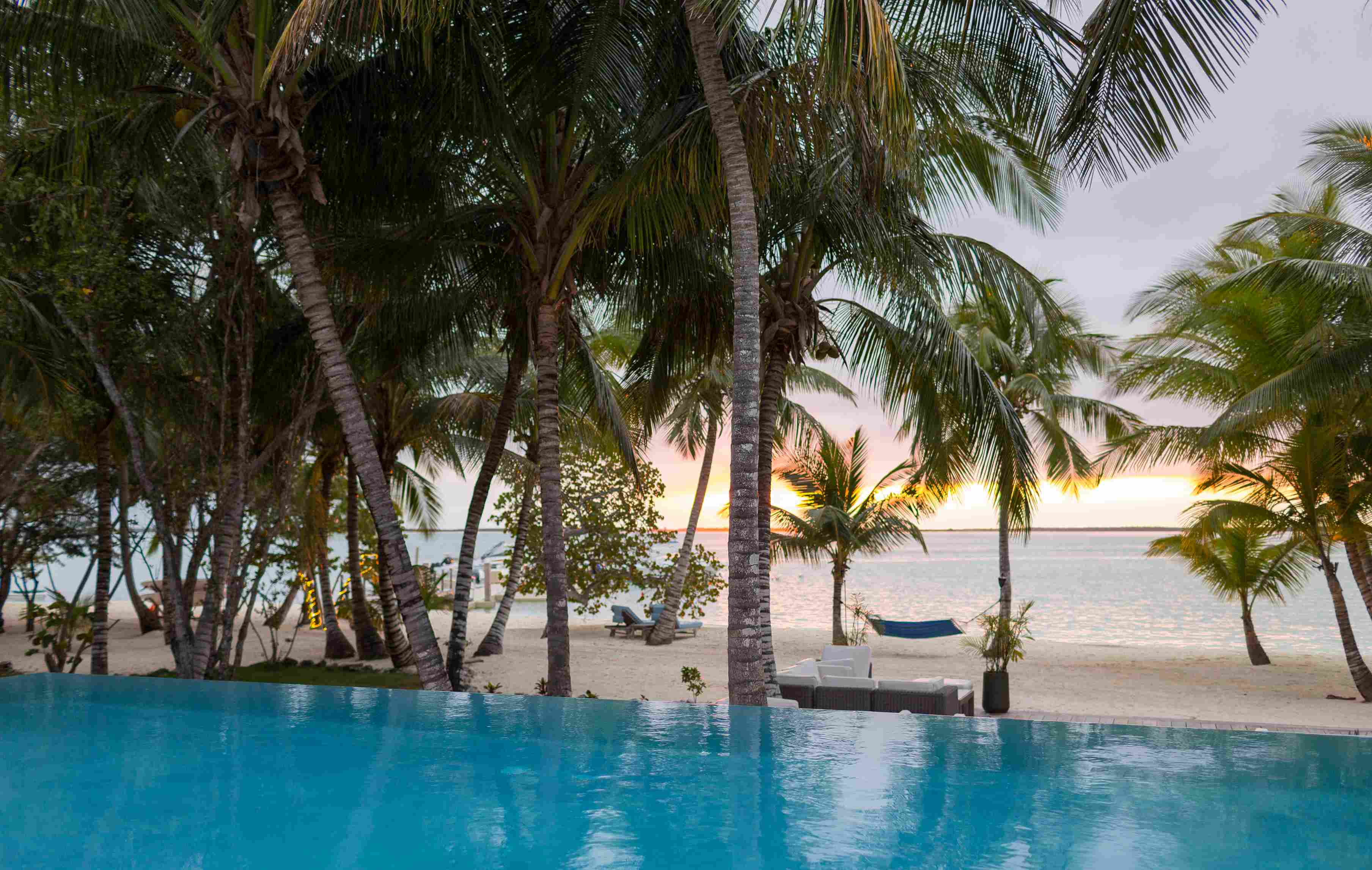 Infinity-Pool am Sansibar-Strand bei Sonnenuntergang mit Palmen
