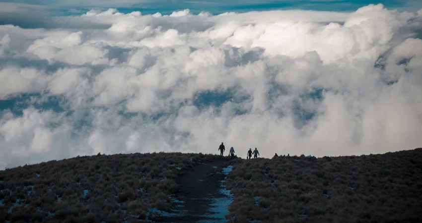 Trekker-Silhouetten über dem Wolkenmeer auf dem Weg zum Kilimandscharo-Gipfel